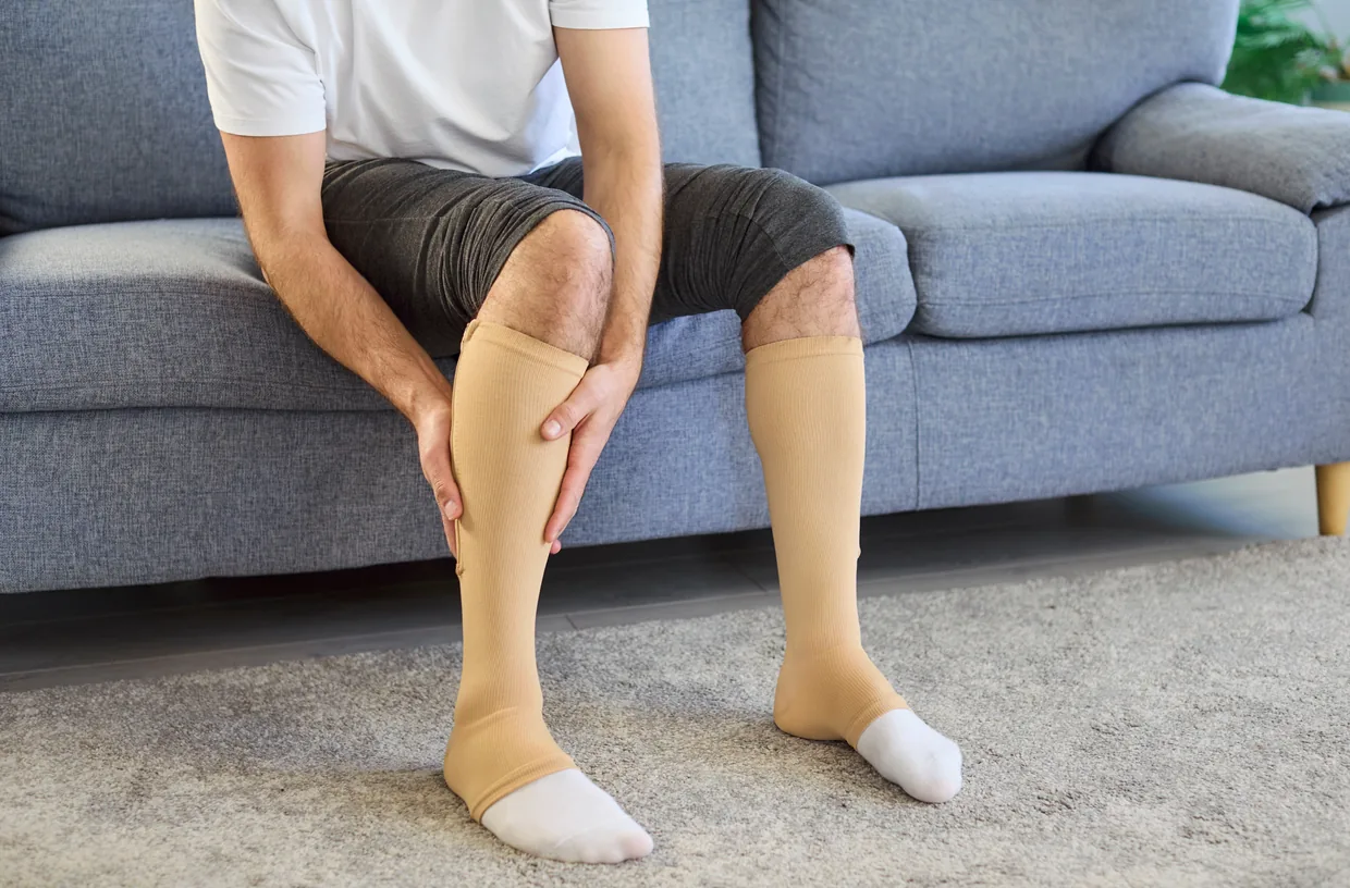 A man wearing compression stockings on a sofa